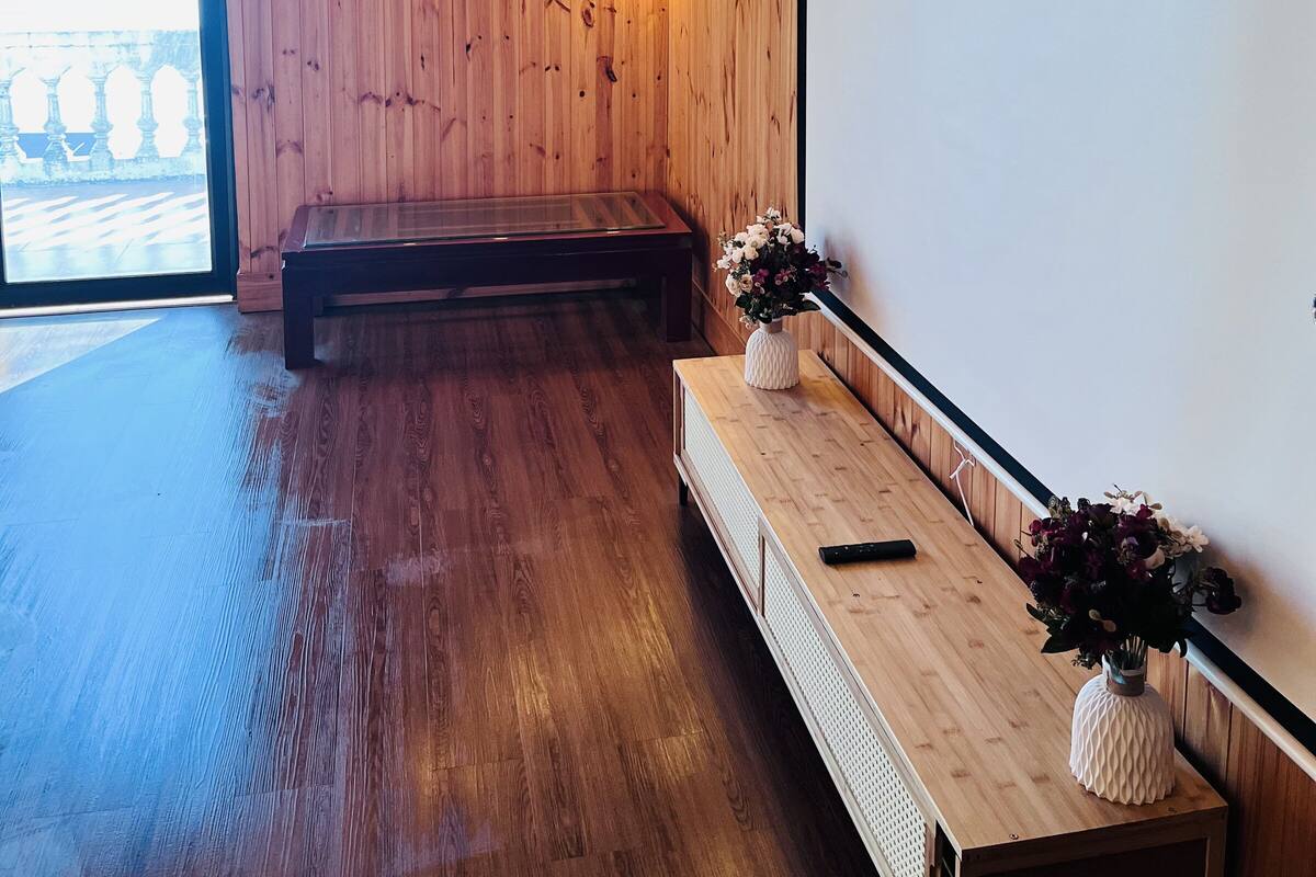 A room with wooden walls, a bench, a whiteboard, and a wooden table with a vase of flowers.