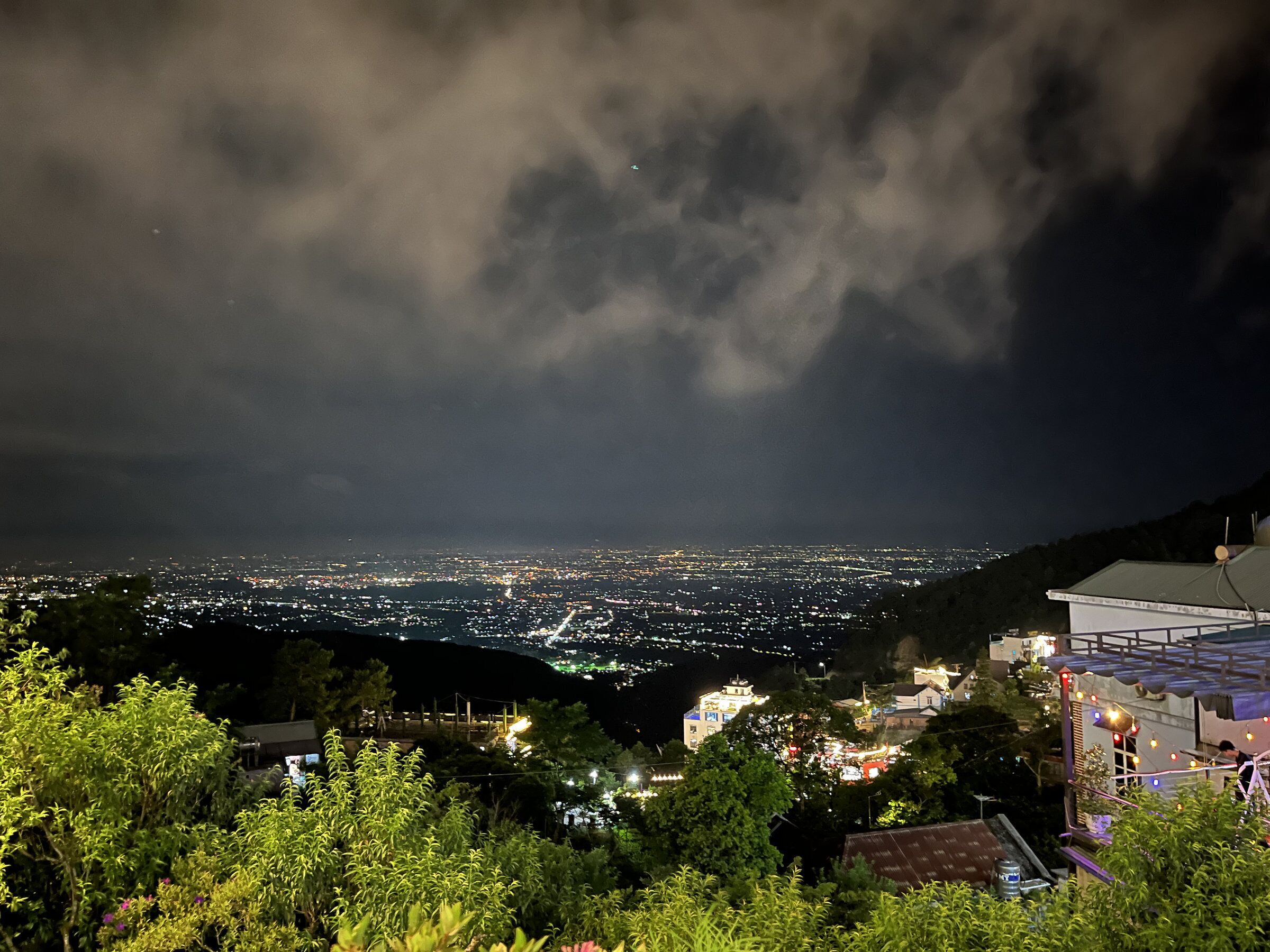 A nighttime cityscape with buildings and a mountainous backdrop.