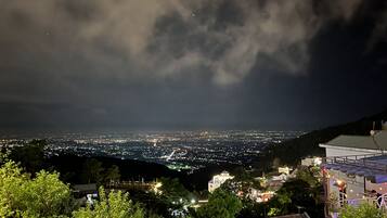 A nighttime cityscape with buildings and a mountainous backdrop.