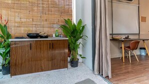 Cocina moderna con encimera de madera, un lavamanos y una estufa. Hay plantas en macetas y una ventana con persianas.