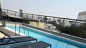 A rooftop pool area with three sun loungers and a swimming pool. - Studios Expo Stay  (São Paulo)