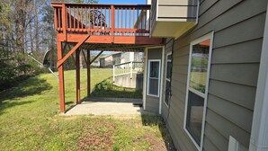 A house with a wooden deck, a concrete pathway, and a door leading to a garage.