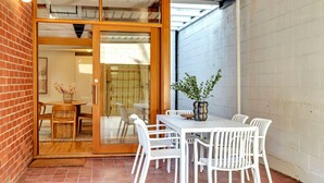 Eine Terrasse mit Tisch und Stühlen, eine Schiebetür und ein Blumentopf.