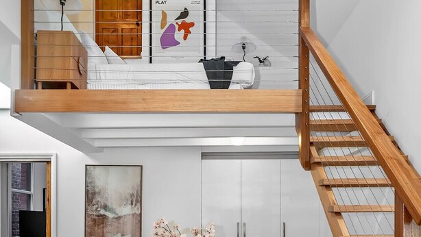 Ein Loft-Zimmer mit Essbereich, einer Treppe und Blick auf die Stadt.