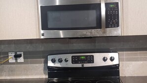 A kitchen with stainless steel appliances, including a microwave and an oven. - Room-standard Bedroom With King Size bed (Lethbridge)
