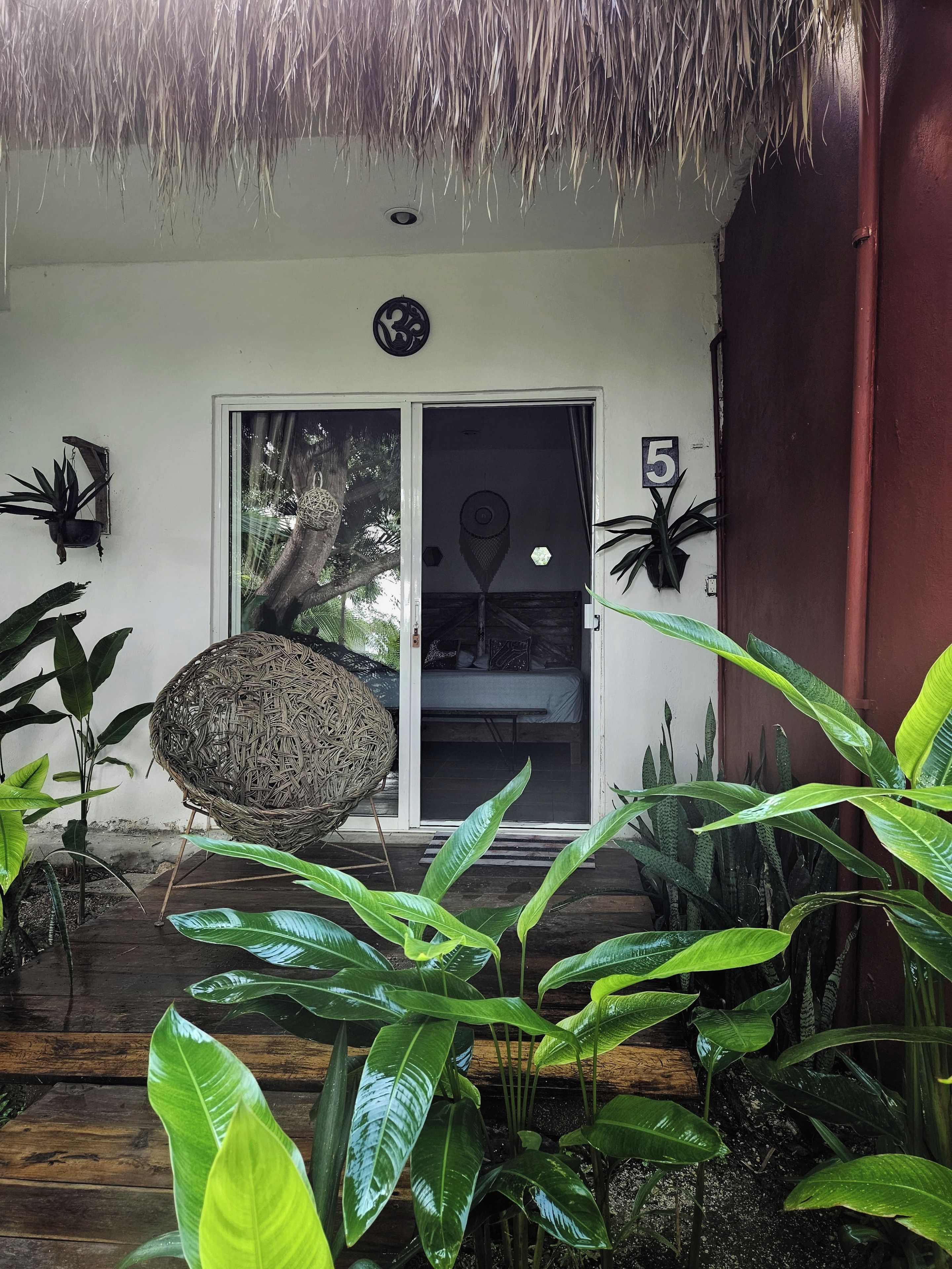 A covered porch with a thatched roof, a sliding glass door, and a number '5' sign.