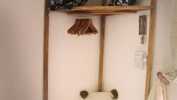 Habitación de esquina con un banco de madera, un perchero colgante y un pequeño estante con cojines estampados.