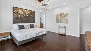 A modern bedroom with a large bed, a unique ceiling light, and decorative wall art.