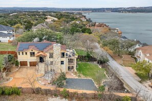 A residential area with a house featuring a stone facade, a solar panel roof, and a large yard with a swimming pool.