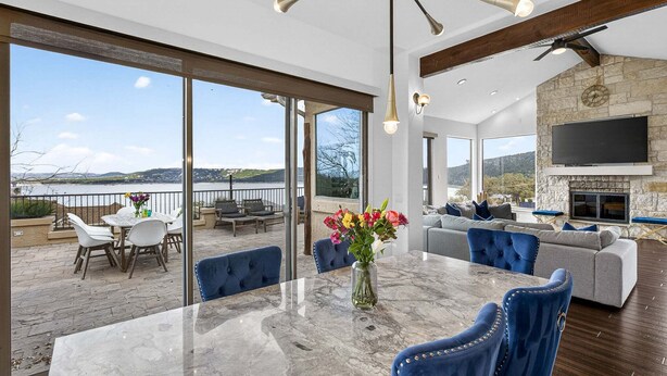 A spacious living area with a large table, blue chairs, a sofa, and a fireplace.