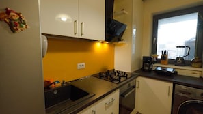 Uma cozinha compacta com fogão a gás, forno embutido e máquina de lavar louça.