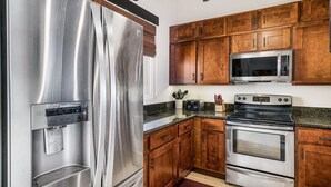 A kitchen with stainless steel appliances, wooden cabinets, and a built-in water dispenser. - Surf & Racquet 3-301 Oceanfront 3BR Penthouse | Views, Lanai, AC (Kailua Kona)