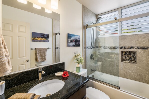 Un baño con lavamanos, espejo, ducha y vistas al exterior.