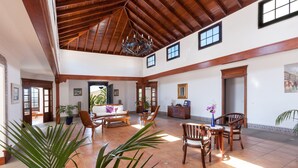 A spacious interior with a high ceiling, wooden beams, and a chandelier. There are multiple seating areas with chairs and a sofa. - Bellavista private heated pool and sauna (Valles, Los)