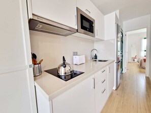 A modern kitchen with white cabinetry, a stainless steel kettle, a microwave, and a toaster. - Casa Marisa in Puerto del Carmen (Puerto Del Carmen)