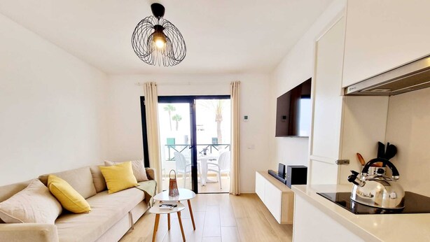 Un salon moderne avec un canapé, une petite table, une bouilloire et un téléviseur.