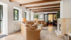 Ein geräumiges Wohnzimmer mit Kamin, Ledersofas und Holzboden.