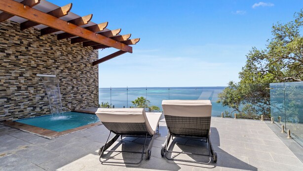 Un espace aménagé au bord de la piscine, avec deux chaises longues et un mur en pierre.