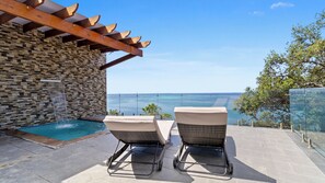 Un área junto a la piscina con dos sillones de descanso y una pared de piedra.