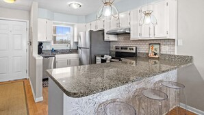 A modern kitchen with white cabinets, granite countertops, and stainless steel appliances. - New! Bayfront Condo w/ 2 Balconies, Loft & Pool – Walk to Beach (Fort Walton Beach)