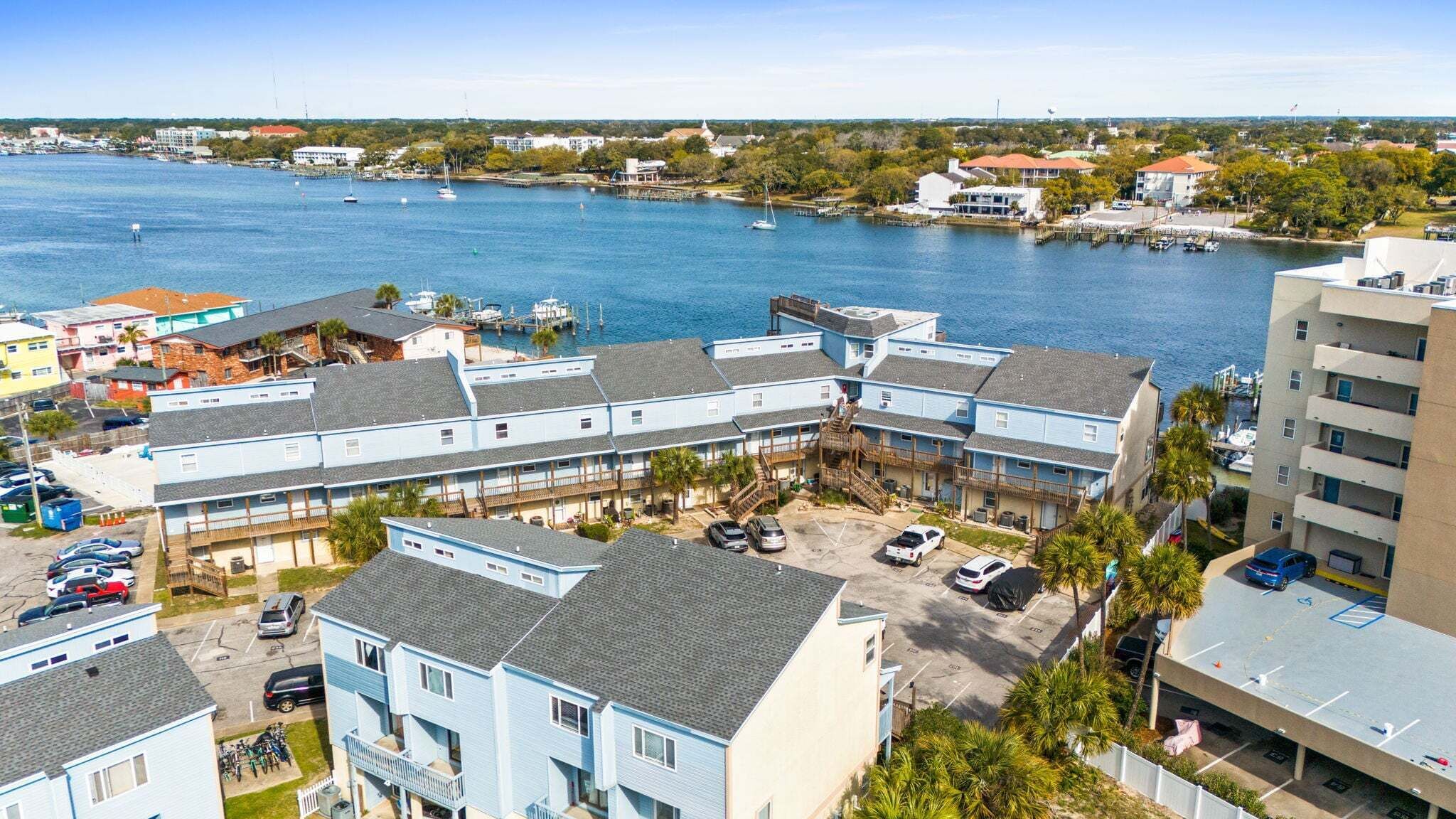 Un hotel frente al mar con edificios de varios pisos, un puerto deportivo con barcos y vistas despejadas al agua.