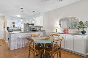 A kitchen with white cabinets, a marble island, wooden chairs, and a round dining table. - New! Bayfront Condo w/ 2 Balconies, Loft & Pool – Walk to Beach (Fort Walton Beach)