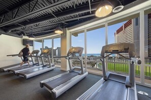 A gym with treadmills and a person using one, large windows, and a view of a building outside. - AMAZING OCEANFRONT VIEWS! Family- Friendly Resort. Just steps from the beach!!🏝️ (Panama City Beach)
