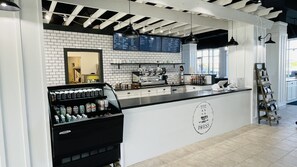 A cafe interior with a black counter, white tiled walls, a coffee machine, and a menu board. - AMAZING OCEANFRONT VIEWS! Family- Friendly Resort. Just steps from the beach!!🏝️ (Panama City Beach)