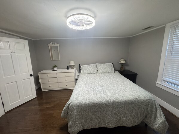 A bedroom with a bed, dresser, mirror, and a ceiling light fixture.