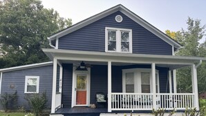 Une maison à deux étages avec un porche, une porte d’entrée et un petit jardin.