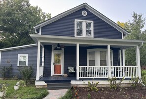 A two-story house with a porch, a front door, and a small garden area.