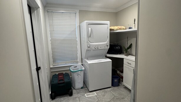 Une buanderie équipée d’un lave-linge, d’un sèche-linge et d’une petite étagère où sont rangés divers objets.