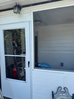 A white door with a glass panel, a ladder, and a red bucket inside.