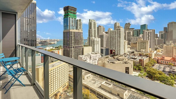 Een hoog gebouw met een balkon en een uitzicht op de stad, onder een heldere lucht.