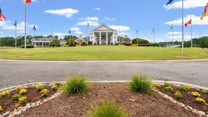 A large building with a central entrance, surrounded by a well-maintained lawn and flower beds. - Stylish Myrtle Beach Retreat, Golf Views • Pool • Near Beach and Broadway (Myrtle Beach)