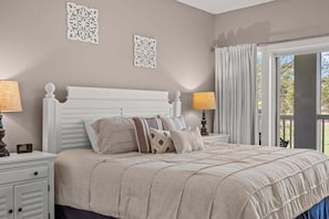 Ein Schlafzimmer mit einem Bett, Nachttischen, Wanddekoration und Blick durch ein Fenster.