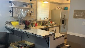 Une cuisine compacte dotée d’un îlot central intégré, d’un réfrigérateur et d’une poubelle.