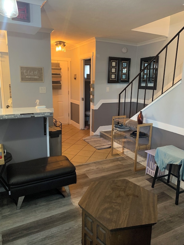 A modern living room with a wooden bench, a small table, and a staircase leading to an upper level.
