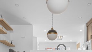 Une cuisine moderne avec un tabouret de bar, un plancher en bois et un luminaire suspendu.