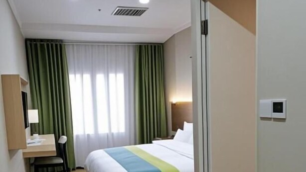 A hotel room with a bed, a desk, a chair, a suitcase, and a door. - Qiqiaowu Hotel Xinfadi Subway Station (Beijing)