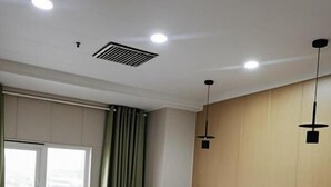 A hotel room with a bed, a window with curtains, a radiator, and a ceiling vent. - Qiqiaowu Hotel Xinfadi Subway Station (Beijing)
