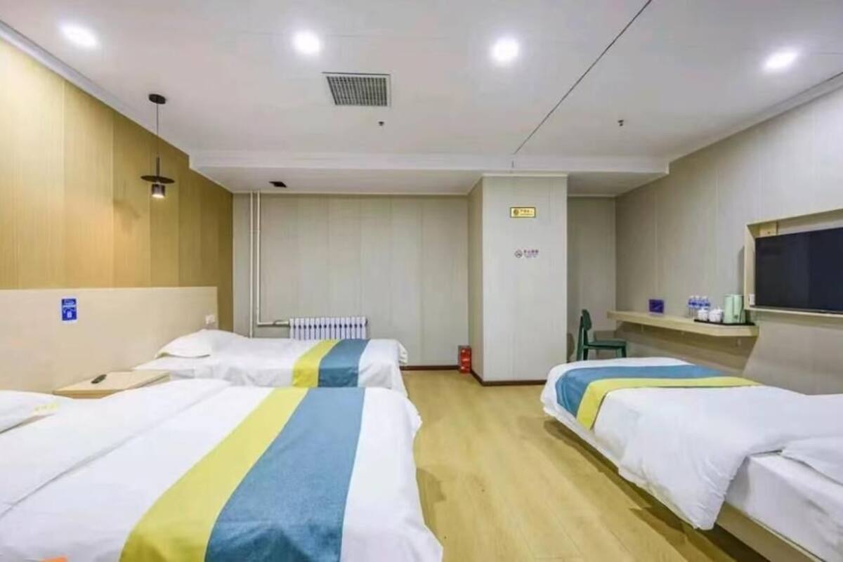 A hotel room with two beds, a television, a small table, and a window.