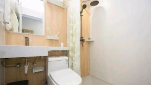 A bathroom with a toilet, sink, mirror, shower, and a towel rack. - Qiqiaowu Hotel Xinfadi Subway Station (Beijing)