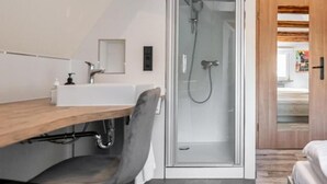 A modern bathroom with a shower, a sink, and a chair. - H M Boarding Houses (Lauf an der Pegnitz)