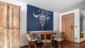 A room with a wooden table and chairs, a large painting of a bull, and wooden doors. - H M Boarding Houses (Lauf an der Pegnitz)