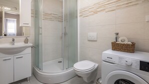 A modern bathroom with a glass-enclosed shower, a toilet, and a washing machine. - Apt Xenia Walk To Beach /w Balcony, Medulin, Croatia (Medulin)