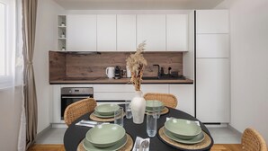 A modern kitchen with white cabinets, a wooden countertop, and a dining area with a round table set for four. - Apt Xenia Walk To Beach /w Balcony, Medulin, Croatia (Medulin)