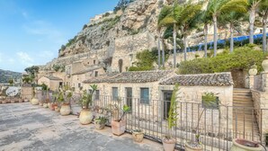 A row of stone buildings with tiled roofs, a metal fence, and potted plants. - Borgo Hedone - Boutique Blu, Scicli, Italy (Scicli)