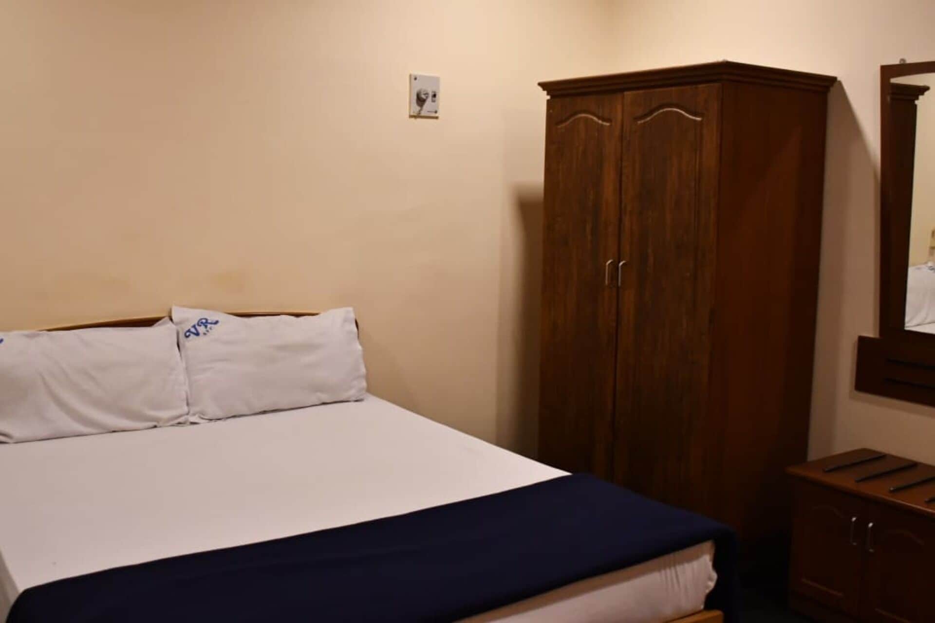 Quarto com cama, guarda-roupa e espelho.