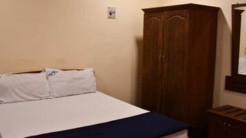 Quarto com cama, guarda-roupa e espelho.